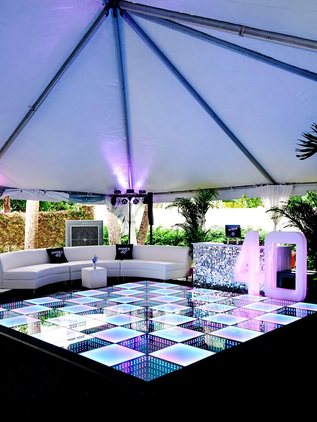 Checkered frosted and infinity LED dance floor under a white tent at a 40th birthday at a private residence in Tampa, with a white lounge sofa and a lit-up 40 sign