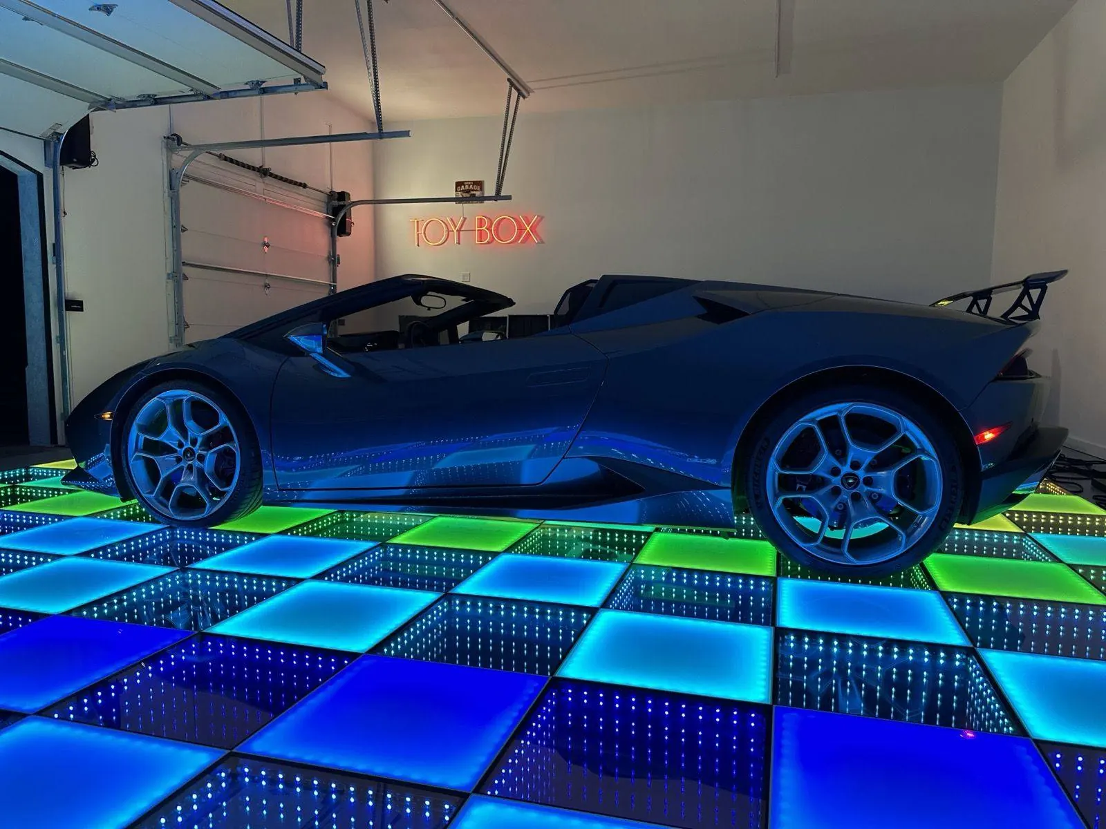 Lamborghini Huracán convertible parked on a blue and green checkered frosted and infinity LED dance floor in a private garage for a car reveal